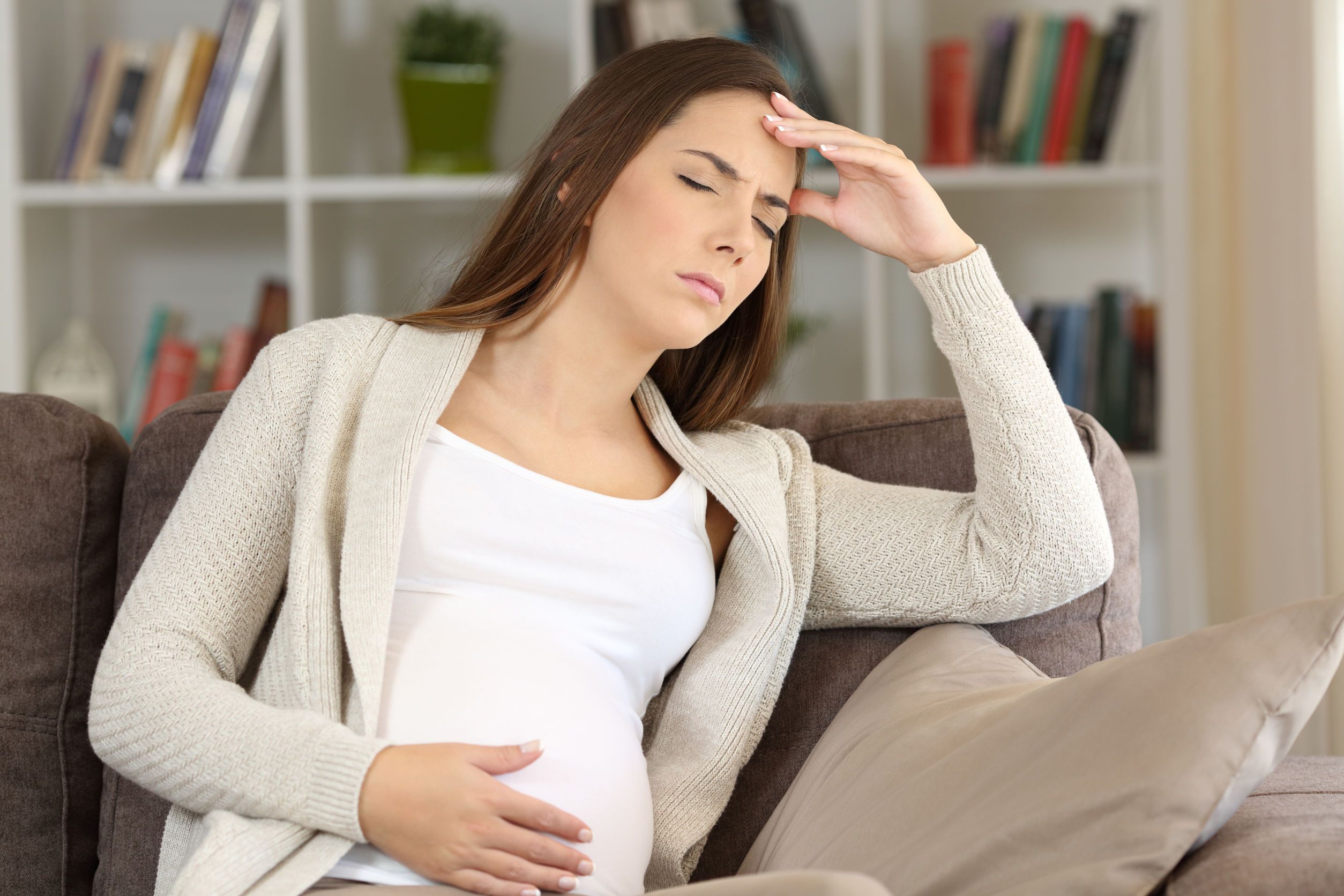 Pregnant woman suffering migraine at home